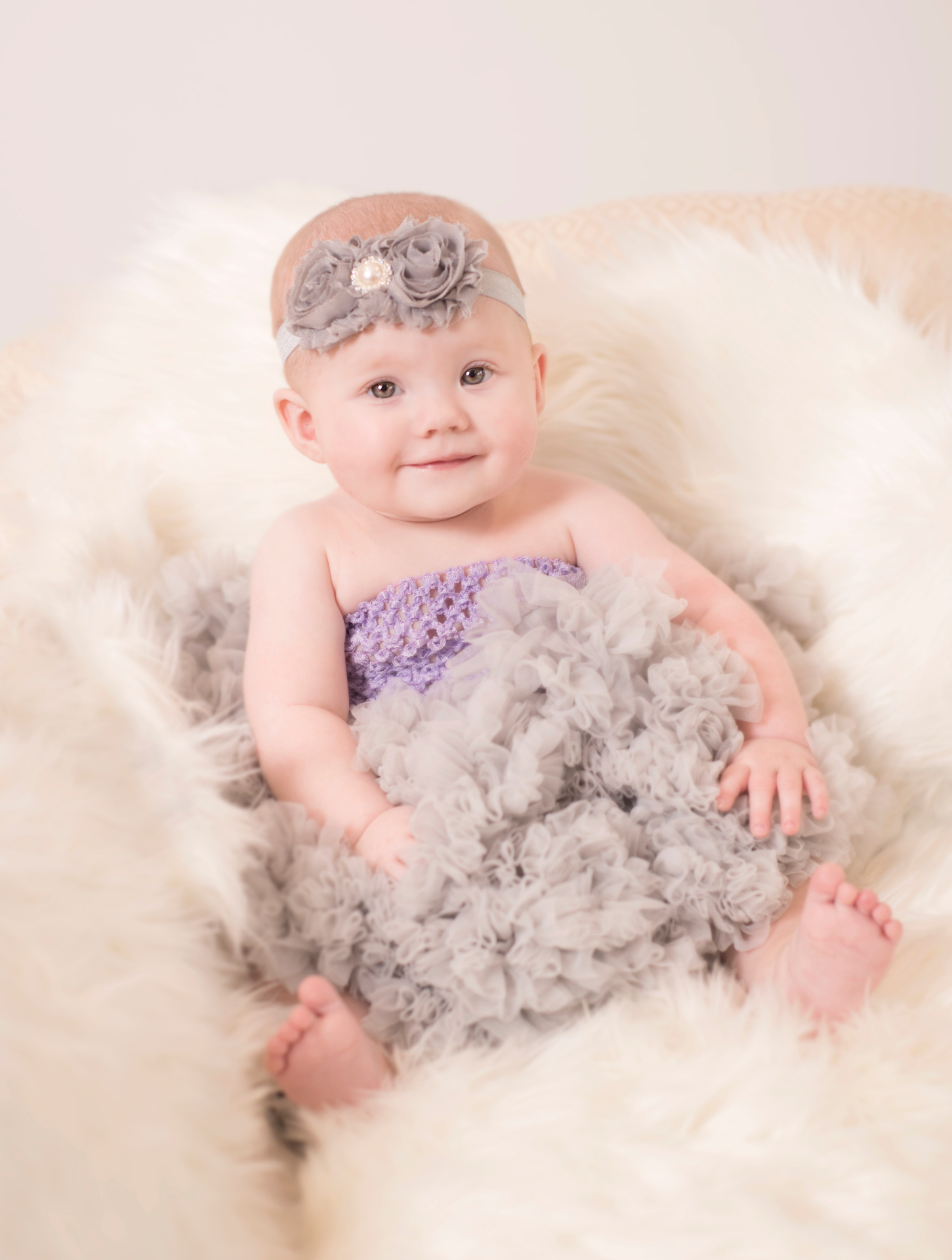 Baby Amber Leah in a soft grey tulle dress on a cream sheepskin