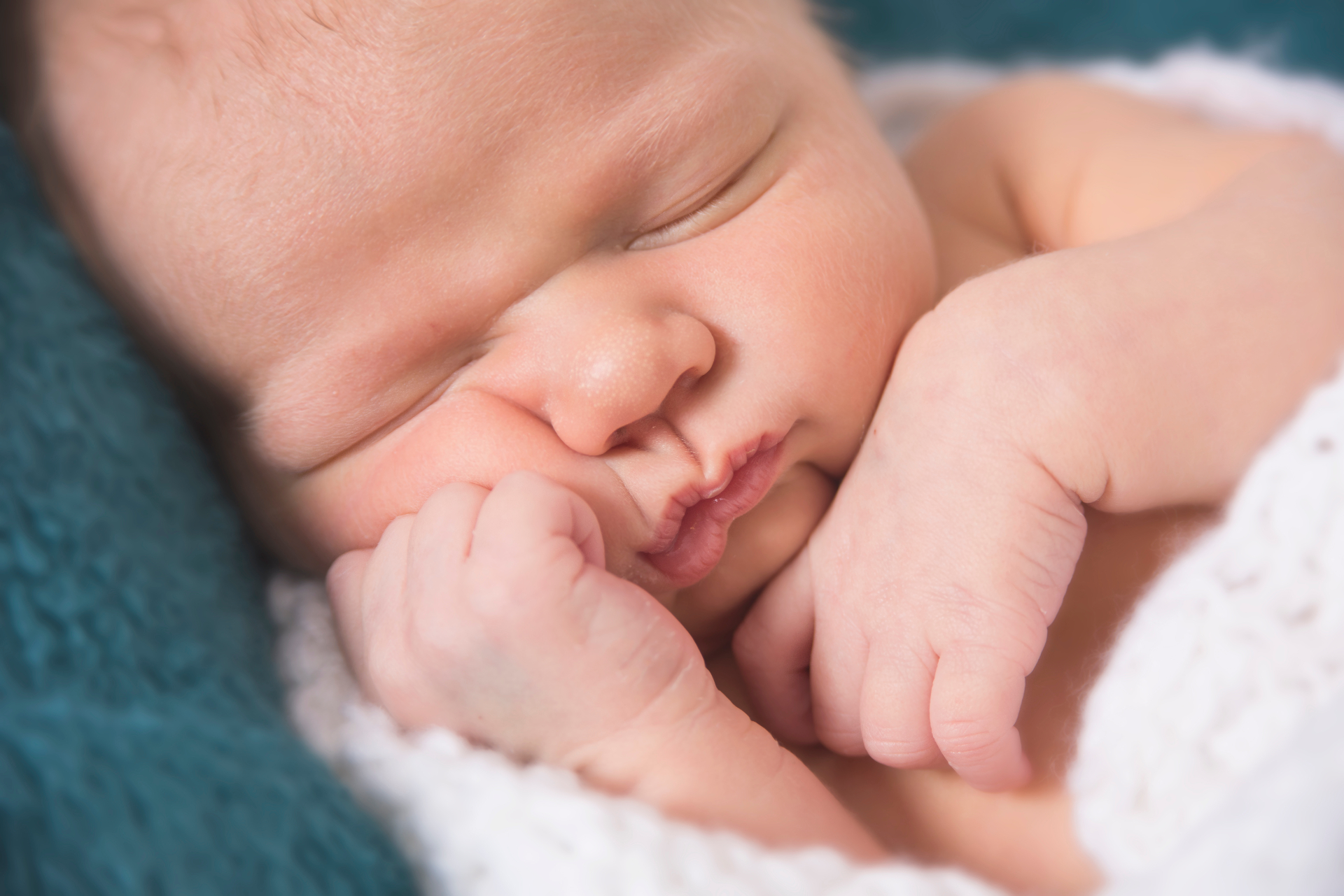 Sleeping newborn Cameron resting on a soft teal blanket