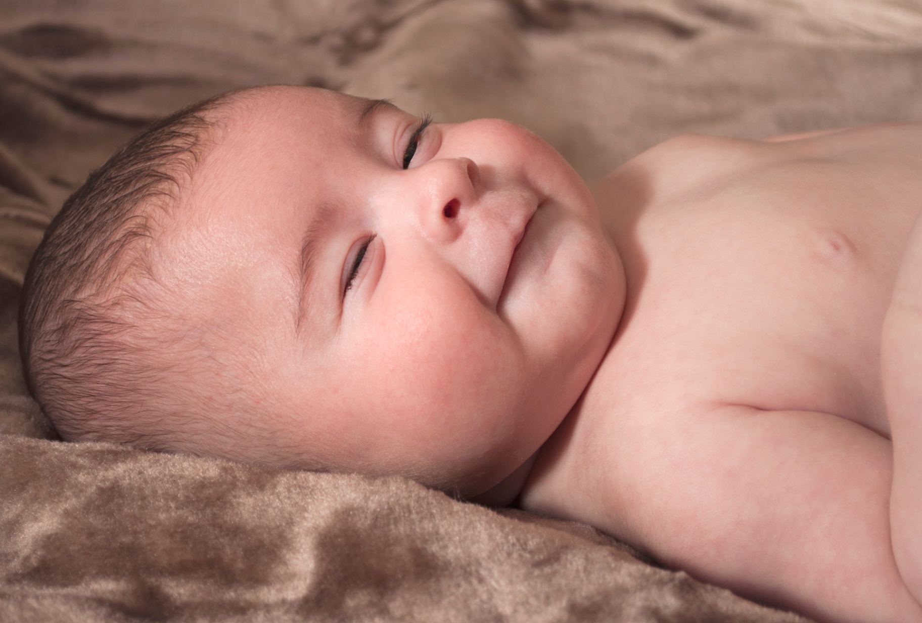 Newborn Dante smiling softly, close-up family portrait